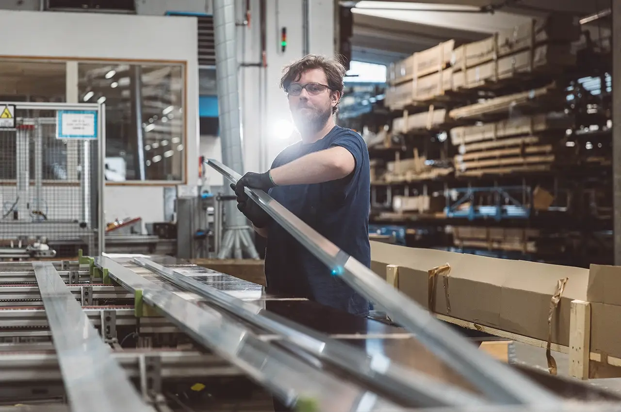 Mitarbeiter beim Entnehmen eines Aluminiumprofils aus der Linie