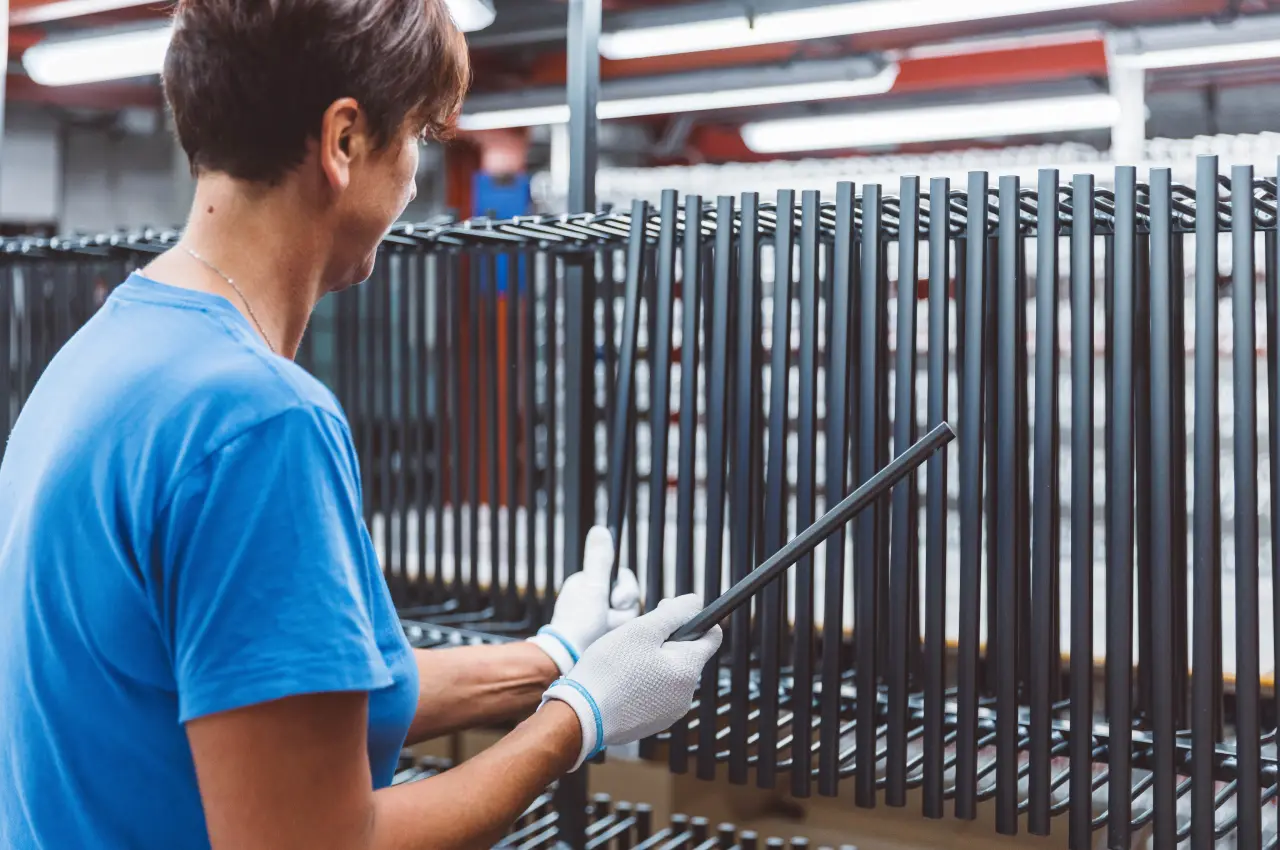 Mitarbeiterin bei der Prüfung von Aluminiumbauteilen auf Warenträgern