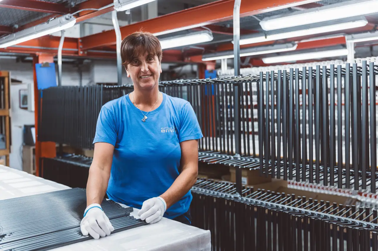 Mitarbeiterin beim Aufhängen von Aluminiumbauteilen vor der Oberflächenbehandlung