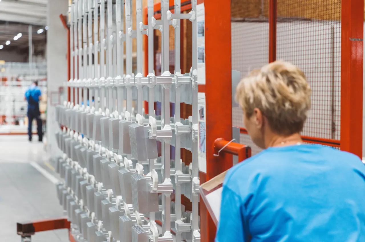 Mitarbeiterin bei der Kontrolle von Aluminiumbauteilen auf Warenträgern