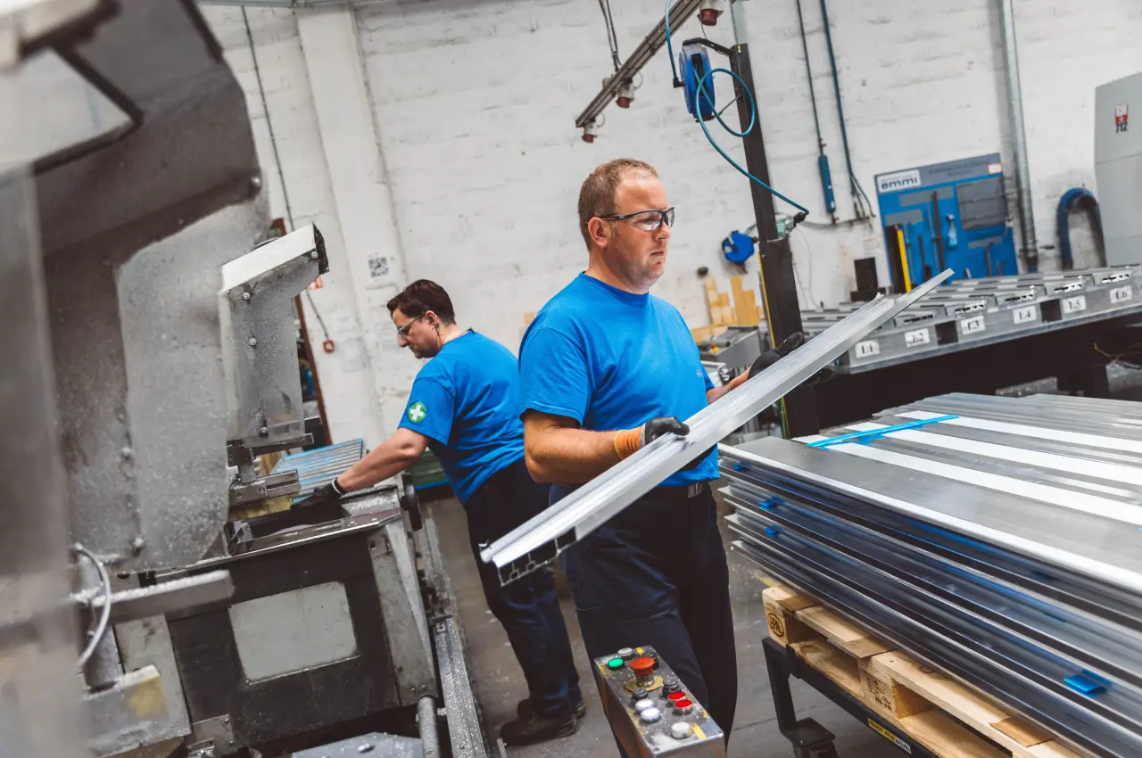 Mitarbeiter bei der Bearbeitung eines langen Aluminiumprofils